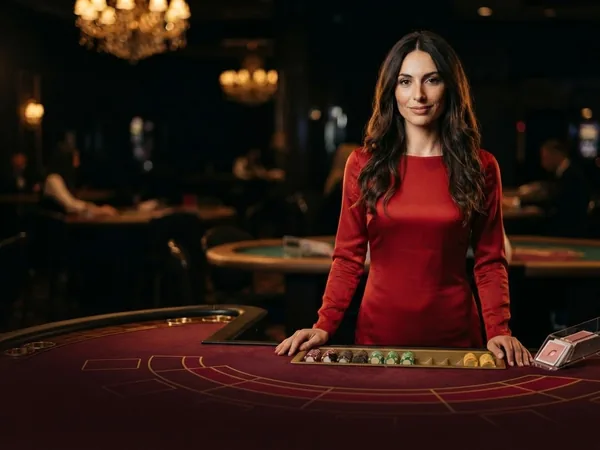 Lobby-style live table card: portrait crop of the croupier red silk studio table, smiling softly